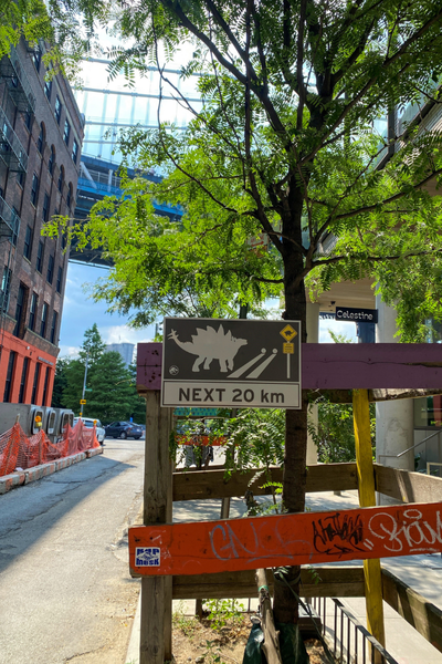 outdoor event wayfinding sign showing "next 20 km" to meet a dinosaur